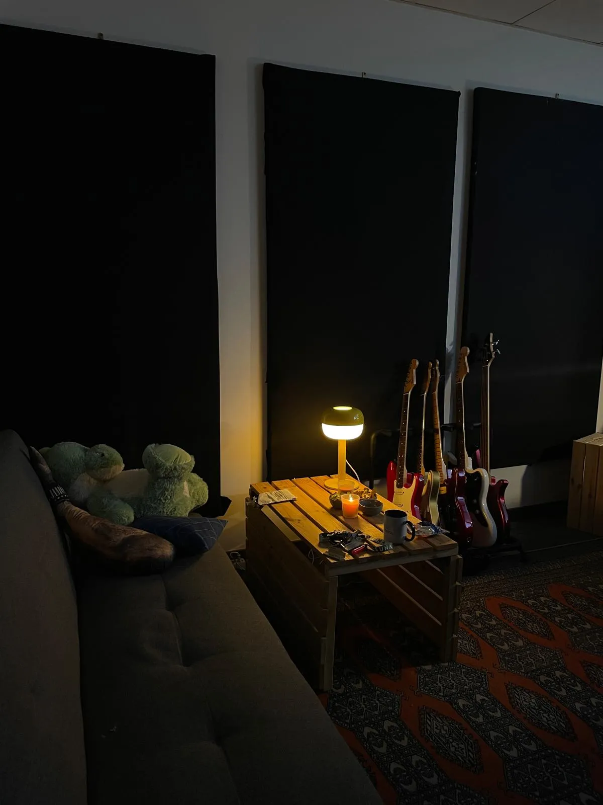 Zona de descanso con sofá, lámpara cálida y guitarras eléctricas
